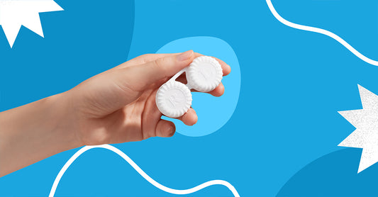 A hand is holding a contact lens storage case