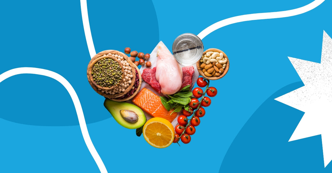 A colorful arrangement of healthy foods on a blue background. The foods include fruits, vegetables, nuts, and whole grains